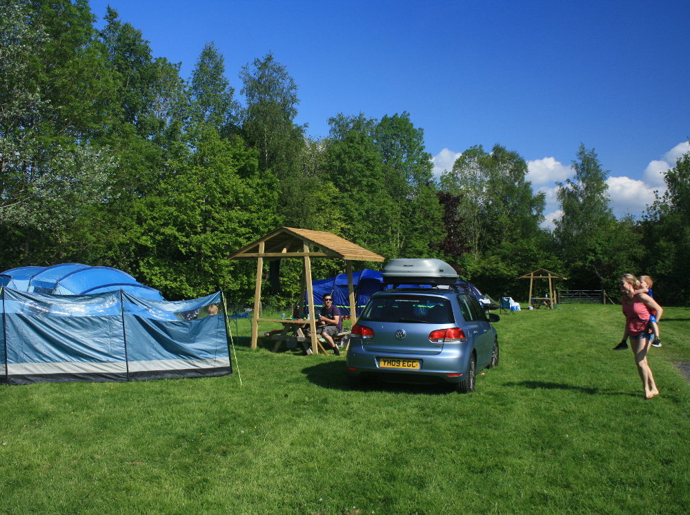 Family enjoying a traditional grass camping pitch at Tyn Cornel Campsite near Bala