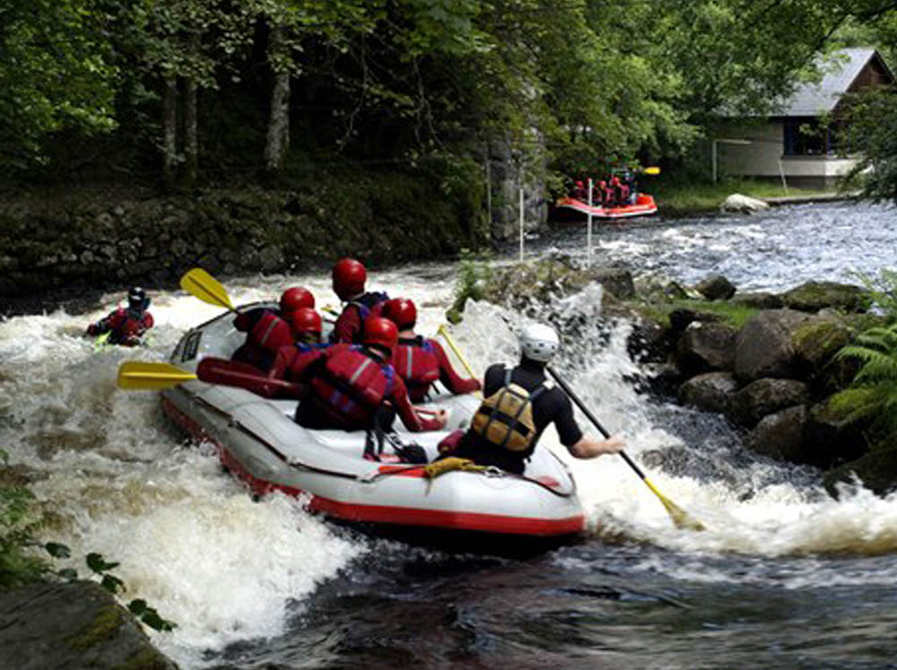 A group enjoying white water rafting past the national Whitewater Centre, Snowdonia National Park